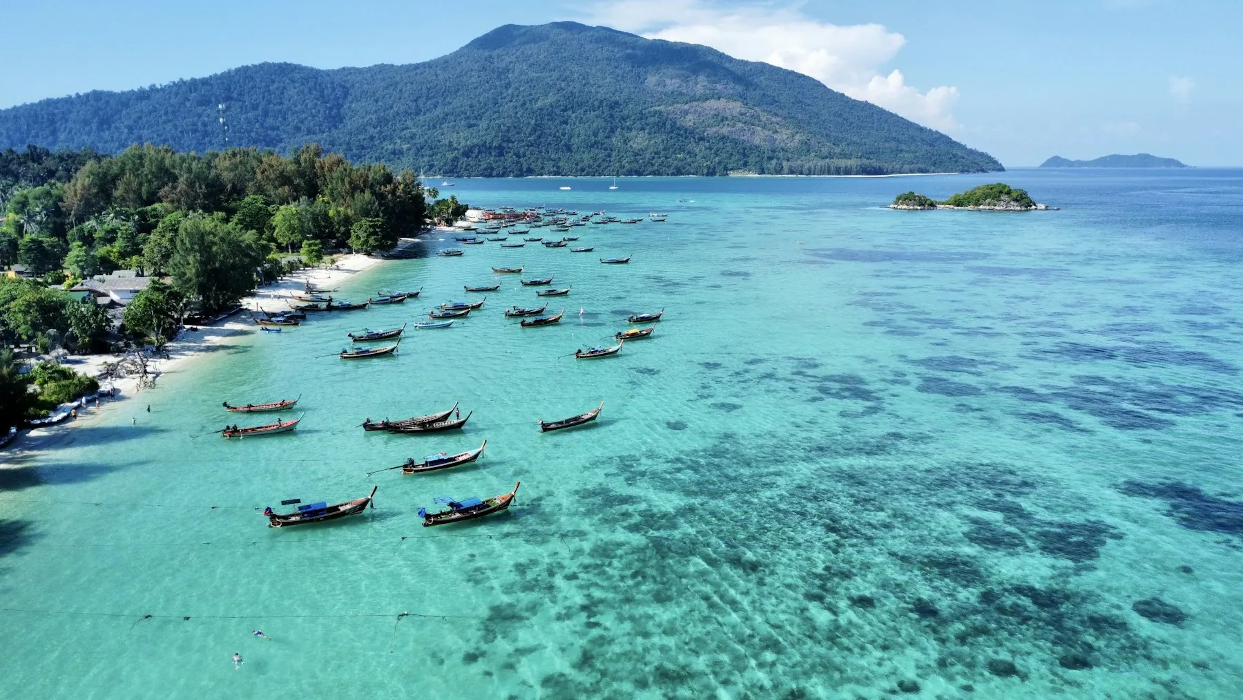 Longtail boats off Koh Lipe, with the mountainous Koh Adang shoreline beyond