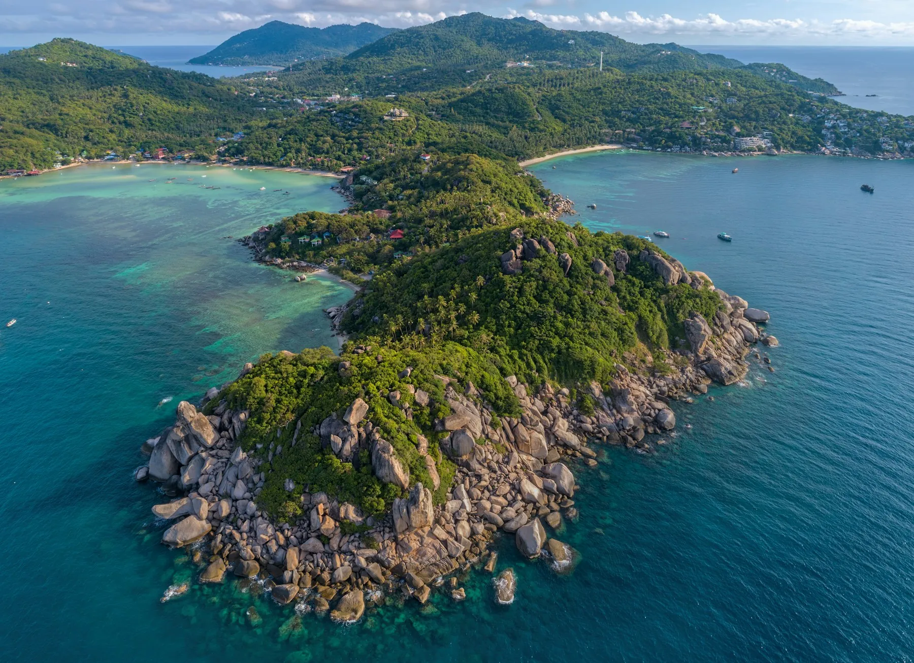 An aerial view of Koh Tao’s rocky, forested headland between two coastal bays