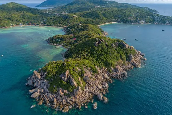 An aerial view of Koh Tao’s rocky, forested headland between two coastal bays