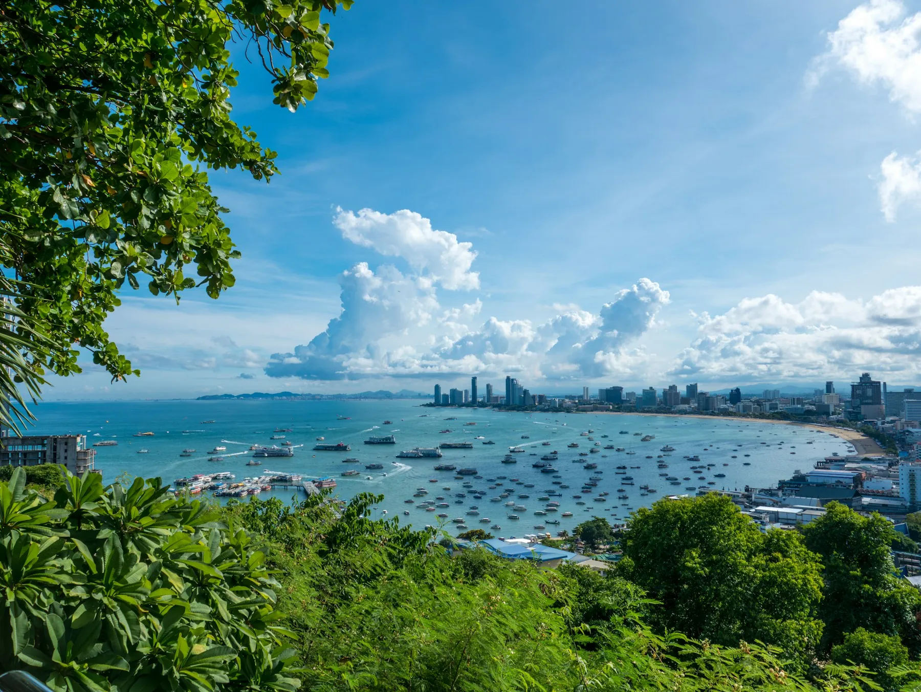 Pattaya Bay with boats, a curved beach and the city skyline seen from Pattaya View Point