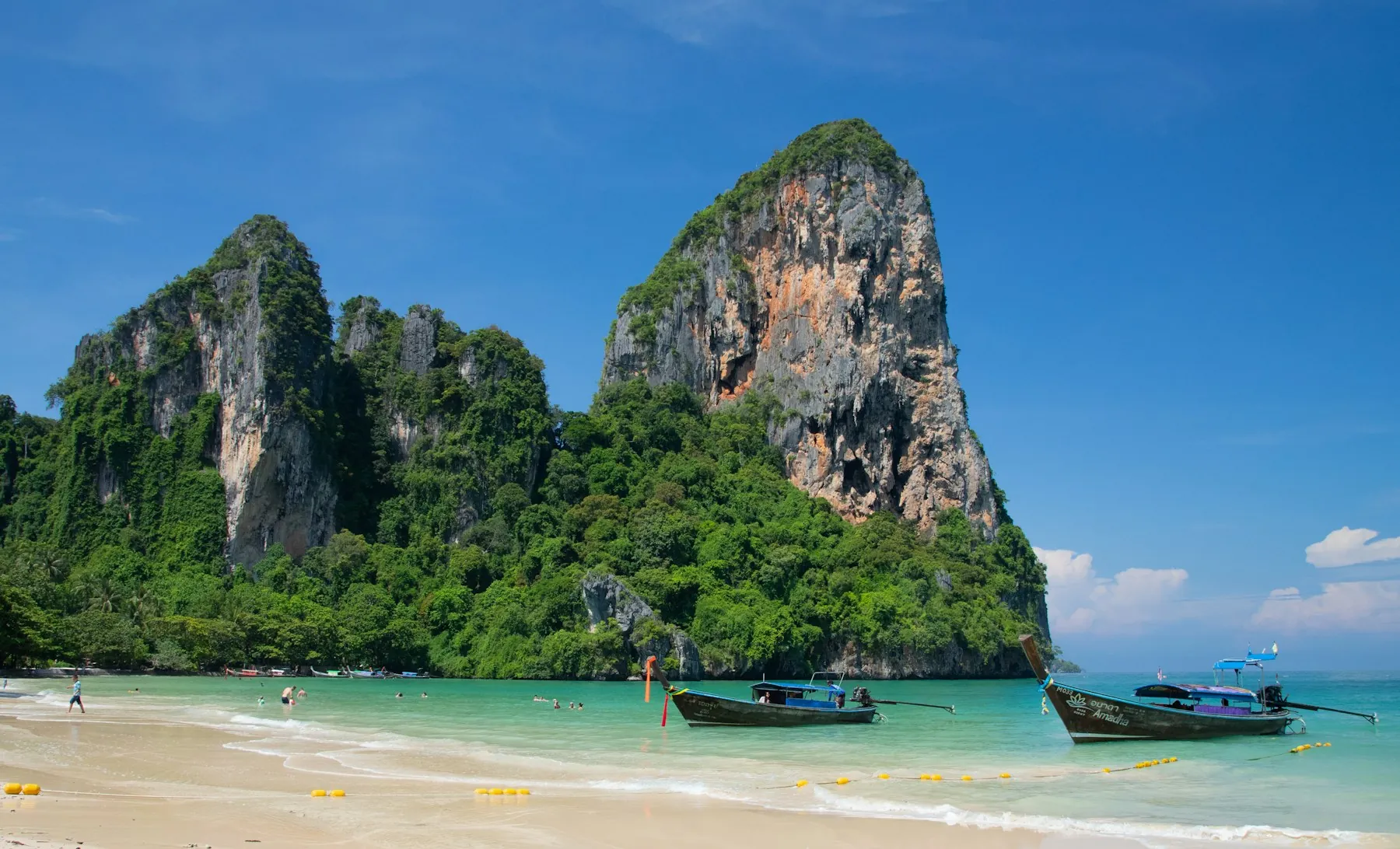 Longtail boats on Railay Beach beneath its distinctive limestone cliffs