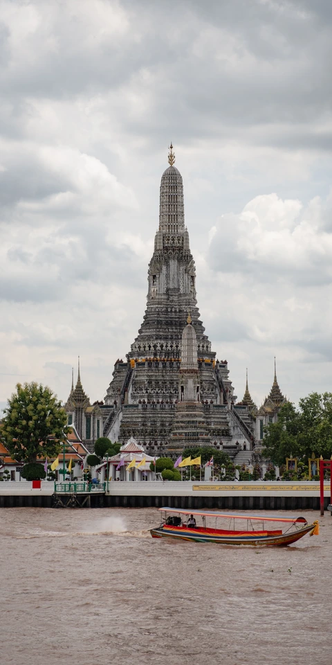 Wat Arun viewed across the Chao Phraya River with a longtail boat in the foreground